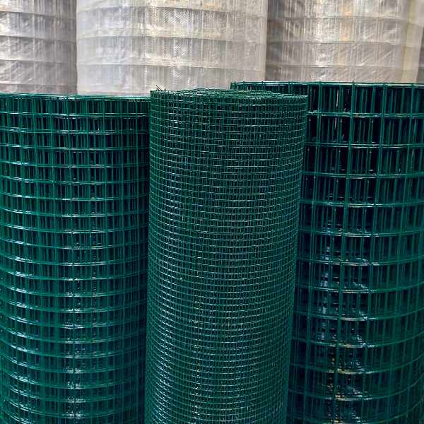 imagem mostrando rolos de tela soldada revestida em pvc verde escuro alinhados na posição vertical no estoque