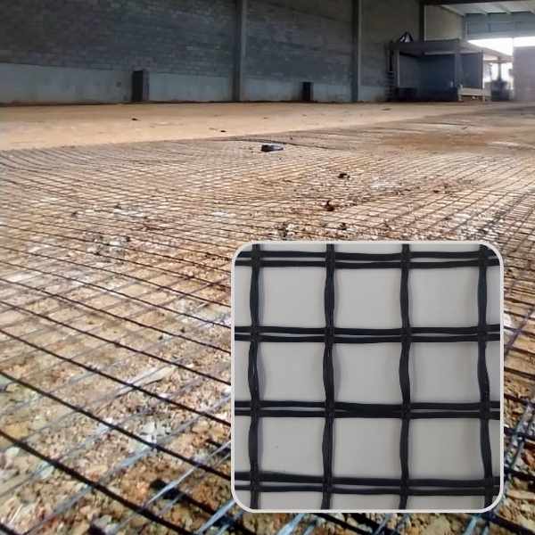 Geogrelha de fibra de vidro aplicada sobre solo compactado em ambiente industrial, com destaque no canto inferior da imagem ampliando o padrão da malha bidirecional.