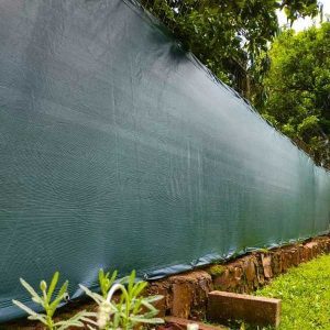 tela de privacidade verde instalada em uma cerca com plantas por perto