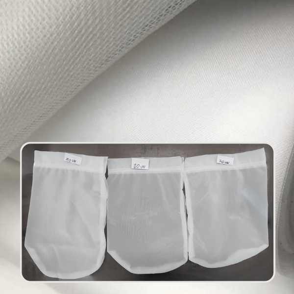 Três bags filtrantes de tela de nylon micronada, identificados com diferentes micragens, posicionados sobre um fundo com rolo de tela branca, usados para filtragem mais fina da água em sistemas de cultivo de peixes e camarão.
